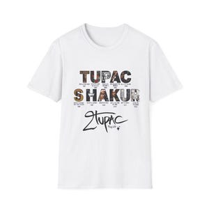 May include: White t-shirt featuring the text "TUPAC SHAKUR" in a multi-colored design. The shirt also includes the signature "2Pac" and album titles. A classic crew neck tee.