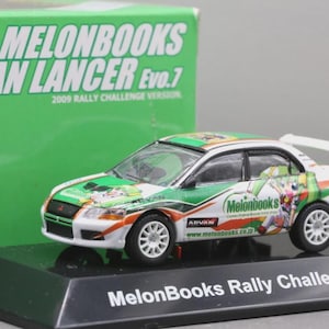 May include: A miniature white, green, and orange rally car with the text "MelonBooks" and "ADVAN LANCER Evo.7" on the side. The car sits on a black base that reads "MelonBooks Rally Challenge 2009". A green box is in the background.