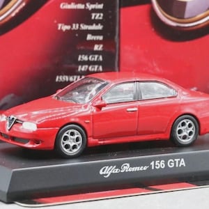 May include: A red Alfa Romeo 156 GTA model car on a black display stand. The model car has silver wheels and is displayed in front of a red background with text.
