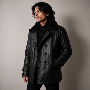 May include: A black leather jacket with a double-breasted design. The jacket has a faux fur collar, button fastenings, and buckle details on the sleeves. The model is wearing a black sweater.
