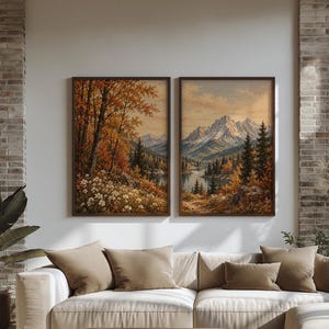 Könnte beinhalten: Zwei gerahmte Landschaftsgemälde mit herbstlicher Bergkulisse, goldenen Bäumen, Nadelwäldern und schneebedeckten Gipfeln, präsentiert an einer weißen Wand über einem beigen Ecksofa mit passenden Kissen und einem hölzernen Couchtisch.