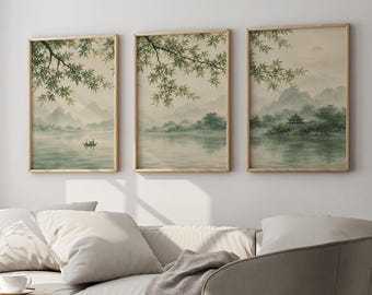 May include: Three framed wall art prints featuring a serene landscape with green-toned mountains, a calm lake, overhanging tree branches, a small boat, and a traditional pagoda structure, all displayed in light wooden frames on a plain white wall.