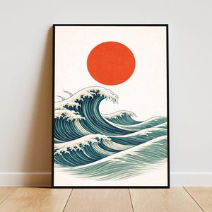 May include: A framed rectangular wall art print featuring a stylized illustration of dark teal ocean waves with white foam crests set against a cream background, topped with a large, solid red circle representing a sun in the upper center.