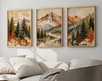 May include: Three vertical framed wall art prints featuring watercolor-style mountain landscapes with pine trees, rocky peaks, and calm water in shades of rust, forest green, cream, and brown, displayed in a row on a plain light-colored wall.