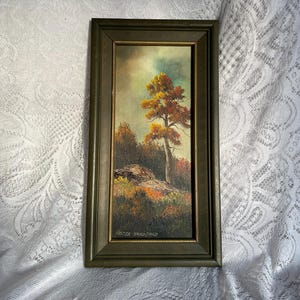 May include: An oil painting in a dark green wooden frame. The artwork depicts a tree with orange and yellow leaves, set against a cloudy sky. The painting is signed "FOSTER HANDFORD" in the lower right corner.