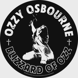 May include: A circular black sticker featuring a white graphic of a person kneeling and holding a cross. The text OZZY OSBOURNE is arched at the top, and BLIZZARD OF OZZ is arched at the bottom, with small crosses separating the phrases.