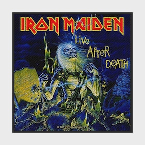 Pode incluir: Um emblema de tecido quadrado com a arte do álbum Live After Death do Iron Maiden. O design mostra uma figura semelhante a um zumbi saindo de um túmulo com o texto amarelo Iron Maiden e Live After Death sobre um fundo azul escuro.