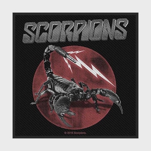 May include: A black fabric patch featuring the word SCORPIONS in grey block letters at the top. Below, a detailed black scorpion is centered over a dark red circle with white lightning bolt graphics. The text 2018 Scorpions is at the bottom.