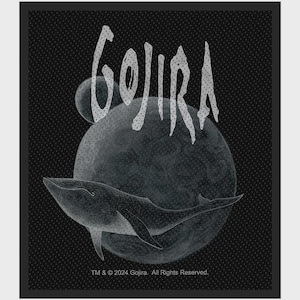 May include: A black fabric patch featuring a white graphic of a whale swimming in front of a large moon and a smaller planet. The text GOJIRA is printed in a stylized white font at the top, with TM & © 2024 Gojira. All Rights Reserved. at the bottom.