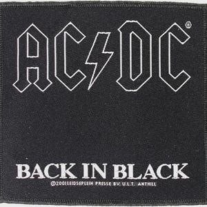 May include: A square black fabric patch featuring the white embroidered AC/DC logo at the top and the text BACK IN BLACK below it. The bottom edge includes the small white printed text 2001 LEIDSEPLEIN PRESSE BV. U.L.T. ANTHILL.