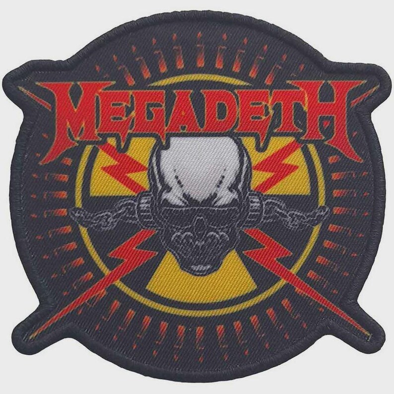 May include: A circular embroidered patch featuring the red text MEGADETH across the top. The centre displays a white skull with black shading, wearing dark sunglasses, set against a yellow radiation symbol and red lightning bolts on black.