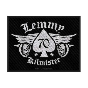 May include: Black patch with a silver design featuring the words "Lemmy Kilmister" and a large ace of spades with the number 70. The design includes wings, skulls, and cross symbols. The patch has a textured background.