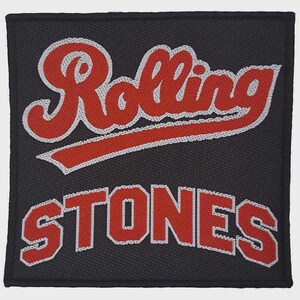 Könnte beinhalten: Ein quadratischer, schwarzer, bestickter Aufnäher mit dem Schriftzug Rolling Stones in rotem Garn und weißem Rand. Das Wort Rolling ist in einer Schreibschrift gehalten, während das Wort Stones in fetten Blockbuchstaben dargestellt ist.