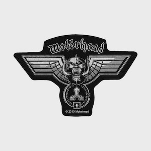 Può includere: Una toppa ricamata in bianco e nero con il testo motorhead in carattere gotico sopra un grafico centrale raffigurante un teschio con corna e ali. Sotto il teschio si trova un emblema circolare con una freccia a tre punte e il testo 2010 Motorhead.
