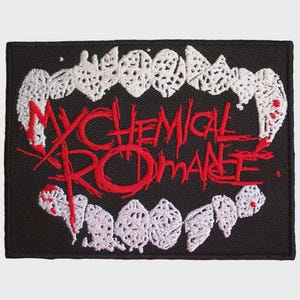 Peut inclure: Un écusson rectangulaire brodé noir présentant des crocs blancs sur les bords supérieur et inférieur. Au centre, le texte My Chemical Romance est brodé dans une police rouge vif dentelée à l'aspect usé et dessiné à la main.