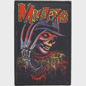 May include: A rectangular embroidered patch featuring a graphic of a skeletal figure wearing a fedora and a glove with long blades. The word MISFITS is printed in large, bold red letters at the top. The design uses black, red, and yellow tones.