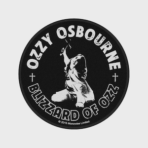 Op de afbeelding: Een ronde zwarte patch met een witte afbeelding van een persoon die knielt en een kruis vasthoudt. De tekst OZZY OSBOURNE en BLIZZARD OF OZZ staat in het wit langs de rand, met kleine kruisjes en 2015 Monowise Limited.