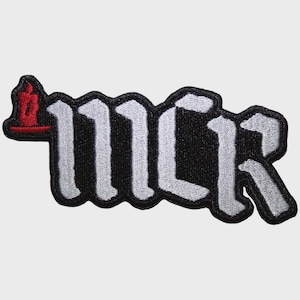 May include: An embroidered patch featuring the letters MCR in a stylised white gothic font with a thick black border. To the left of the letters is a small, red, upright candle icon with a flame, all set against a plain background.