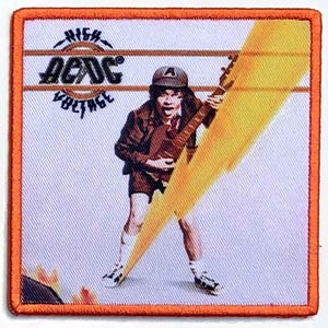 May include: A square embroidered patch with an orange border featuring a graphic of a guitarist wearing a cap and shorts, playing a guitar. A large yellow lightning bolt crosses the image. The text AC/DC High Voltage is printed in black.