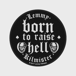 Op de afbeelding: Een ronde zwarte geborduurde patch met witte tekst die luidt Lemmy. born to raise hell Kilmister. Het ontwerp bevat twee witte schedelillustraties en twee kleine schoppensymbolen, met de copyrighttekst 2017 Lemmy Kilmister.