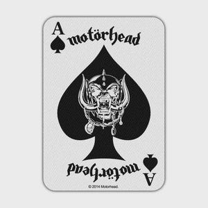 Op de afbeelding: Een rechthoekige speelkaart met een groot zwart schoppensymbool in het midden. Binnenin de schoppen staat een gedetailleerde witte schedelillustratie met hoorns en kettingen. De tekst "motörhead" staat aan de boven- en onderkant van de kaart.