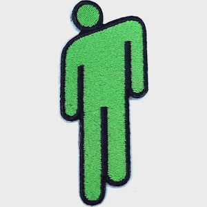 May include: A bright neon green embroidered patch featuring a stylized, minimalist human figure with a circular head and a tilted, blocky torso. The entire design is outlined in a thick, bold black border, creating a high-contrast graphic.