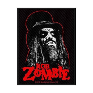 Op de afbeelding: Zwart-wit patch met een portret van Rob Zombie met een hoge hoed, lang haar en een baard. De naam "ROB ZOMBIE" staat in rode blokletters onderaan. De patch heeft een zwarte achtergrond en een rode omtrek.