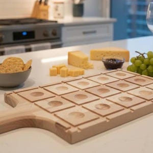 Può includere: Un tagliere in legno con manico, caratterizzato da una griglia di rientranze quadrate. La tavola è circondata da formaggio, cracker, uva e una piccola ciotola di marmellata, suggerendo un tema di salumi.