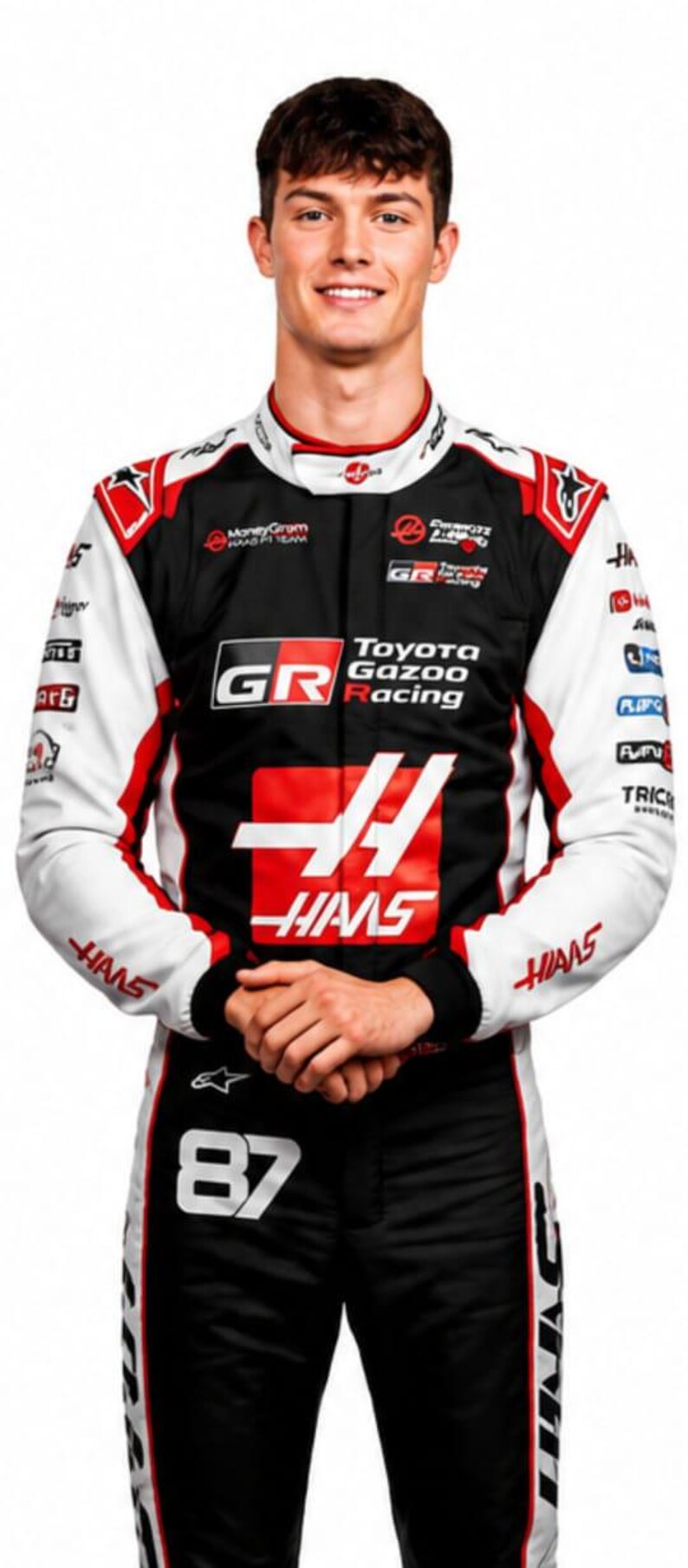 Puede incluir: Una persona con un traje de carreras negro, blanco y rojo con los logotipos de Toyota Gazoo Racing y Haas. El traje tiene el n&uacute;mero 87 en los pantalones. La persona sonr&iacute;e.