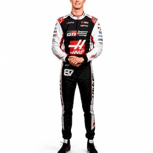 Puede incluir: Retrato de cuerpo entero de una persona con un mono de carreras negro, con detalles en blanco y rojo, y logotipos de Toyota Gazoo Racing y Haas. El n&uacute;mero 87 es visible en el mono. La persona est&aacute; de pie, con las manos juntas.