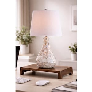 May include: A decorative table lamp with a white lampshade and a pear-shaped base. The base is adorned with iridescent mosaic tiles. The lamp sits on a dark brown wooden stand, adding a touch of elegance to any room.