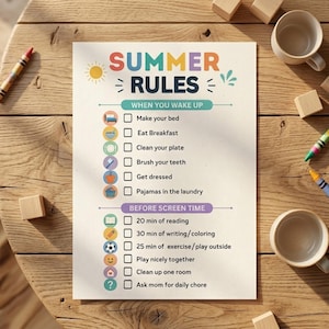 May include: A colorful summer rules checklist on a white paper. The text includes "SUMMER RULES" and daily tasks like making the bed, eating breakfast, and reading for 20 minutes. The paper is on a wooden table with crayons and cups.