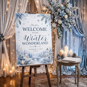 May include: A rectangular welcome sign on a wooden easel featuring a winter wonderland illustration with blue and white tones. The text reads: WELCOME TO OUR Winter WONDERLAND DECEMBER 16, 2026. The design includes pine branches, snowflakes, and a snowy village scene.