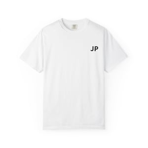 以下が含まれることがあります： 右胸に黒で「JP」のイニシャルがプリントされた無地の白いTシャツ。Tシャツはクルーネックと半袖です。首の後ろに小さなタグが見えます。