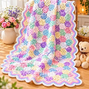 May include: A handmade, colorful crochet blanket with a hexagonal pattern. The blanket features pastel shades of pink, yellow, blue, green, and purple. The edges are scalloped with a rainbow trim. The blanket is approximately 50 inches by 60 inches.