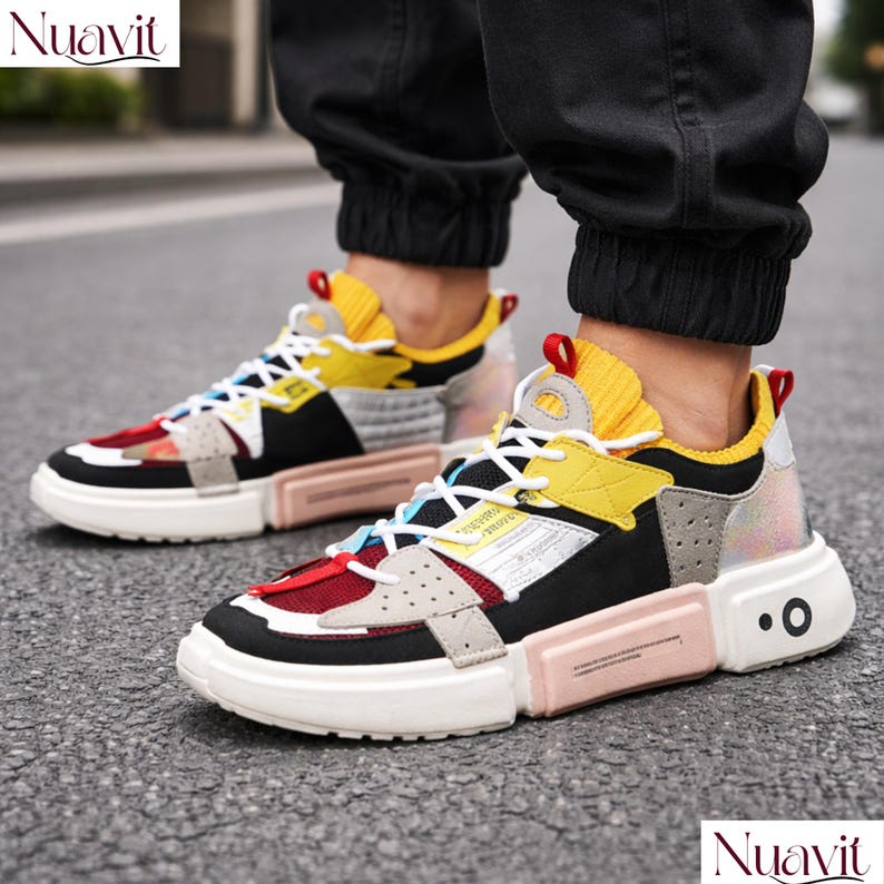 May include: Multi-colored sneakers with a chunky sole. The shoes feature a mix of red, yellow, black, and gray panels, with white laces and a white sole. The design includes a pink mid-sole and a textured yellow collar.