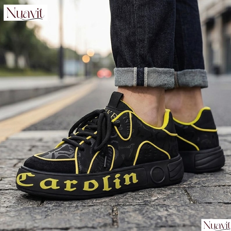 May include: Black sneakers with yellow accents and the word "Carolin" in yellow on the sole. The shoes have a patterned design on the upper and black laces. The brand name "Nuavit" is visible in the top left and bottom right corners.