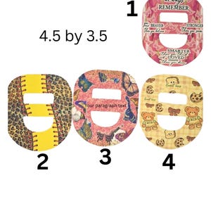 May include: Four decorative, oval-shaped items with cut-out centers. One has a pink floral design with text, another a baseball design, a third with butterflies, and the last with teddy bears and cookies. The items measure 4.5 by 3.5 inches.