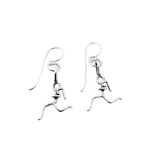May include: A pair of silver earrings featuring a stylized runner design. The earrings are dangle style with a hook closure.