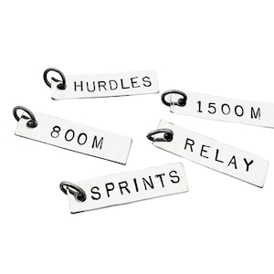 May include: Five silver charms with black lettering, each with a different track and field event: Hurdles, 800M, 1500M, Relay, and Sprints.