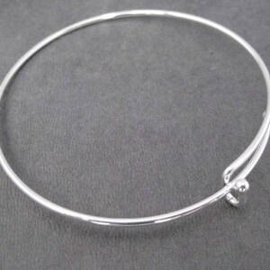 May include: A silver bangle bracelet with a simple, round clasp.