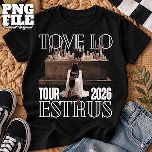 Könnte beinhalten: Ein schwarzes T-Shirt mit einem Grafikdruck einer Person, die vor einem Steinaltar mit Kerzen und einer schwarzen Katze kniet. Der Text lautet TOVE LO, TOUR 2026 und ESTRUS. Die Person trägt ein weißes Kleidungsstück mit ESTRUS auf dem Rücken.