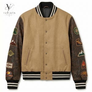 Puede incluir: Una chaqueta estilo universitario de color beige con mangas texturizadas en marrón oscuro, cierre frontal de botones a presión y ribetes acanalados a rayas blancas y negras en cuello, puños y bajo. Las mangas tienen varios parches bordados.