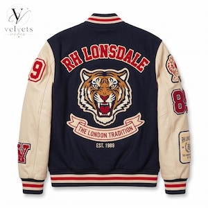 Könnte beinhalten: Eine marineblaue Collegejacke mit cremefarbenen Ärmeln, die auf der Rückseite eine große Tigerkopf-Grafik, den Text RH LONSDALE, THE LONDON TRADITION, EST. 1989 sowie verschiedene rot-weiße Aufnäher mit der Zahl 89 und der Zahl 9 zeigt.