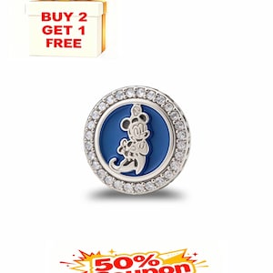 May include: A round, silver charm with a blue center featuring a Mickey Mouse design. The charm is encircled by a row of clear, sparkling stones. The image also includes a gift box with a gold bow and the text "BUY 2 GET 1 FREE".