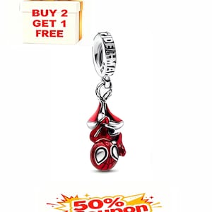 May include: A silver charm with a red and black Spider-Man design. The charm is hanging upside down. The word "SPIDERMAN" is engraved on the top. A gift box with the text "BUY 2 GET 1 FREE" is in the background.
