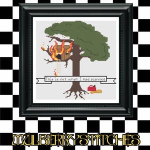Peut inclure: Une broderie au point de croix encadrée montre un arbre avec une cabane en feu. Une bannière indique "This is not what I had planned." Un livre rouge et un objet jaune sont au pied de l'arbre. Le fond est un motif de damier noir et blanc.