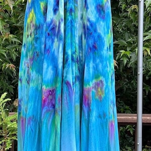 May include: A long, flowing, tie-dye maxi dress with a halter neckline. The dress is a mix of blue, green, and purple shades.