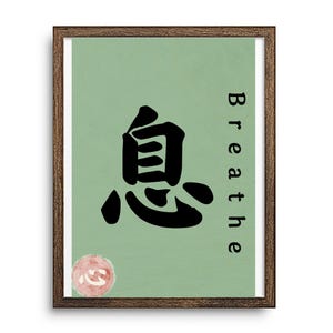 以下が含まれることがあります： 明るい緑色の背景の額入りアートプリント。プリントには、大きな黒い日本語の文字と、黒い文字で「Breathe」という単語が描かれています。ハートのシンボルが付いた小さな円形のデザインが左下にあります。フレームは濃い茶色です。