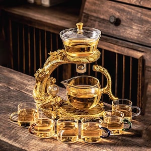 Könnte beinhalten: Set aus drei Keramikbechern mit gesprenkelter, matter Oberfläche. Die Becher sind in Creme-, Hellgrau- und Dunkelgrautönen gehalten. Schlichtes, minimalistisches Design.